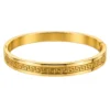 18K gold plated hinged bangle with a raised Greek key pattern around the band on a white background