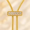 18K gold plated adjustable lariat necklace with a crystal bar slider and two pearl drops on a white background