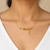 18K gold plated bamboo bar pendant necklace with a small dangling leaf charm on a fine cable chain, on a white background
