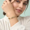 18K gold plated hinged bangle with a row of ten clear crystals and cut-out window details