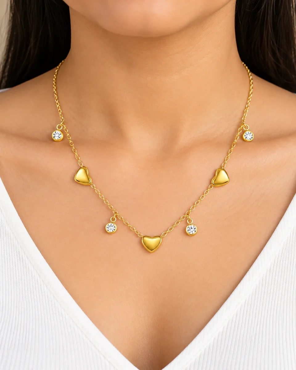 18K gold plated chain bracelet with three puffy heart charms and four bezel-set crystal drops, with lobster clasp and extender, on a white background