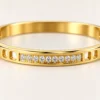 18K gold plated hinged bangle with a row of ten clear crystals and cut-out window details