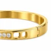 18K gold plated hinged bangle with a row of ten clear crystals and cut-out window details
