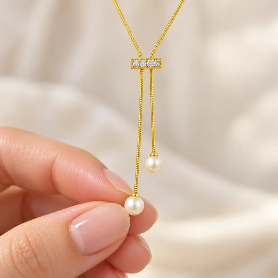 18K gold plated adjustable lariat necklace with a crystal bar slider and two pearl drops on a white background
