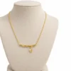 18K gold plated bamboo bar pendant necklace with a small dangling leaf charm on a fine cable chain, on a white background