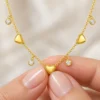 18K gold plated chain bracelet with three puffy heart charms and four bezel-set crystal drops, with lobster clasp and extender, on a white background