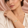 18K gold plated hinged crossover bangle with a bar of clear crystals overlapping a mother-of-pearl inlay on a model
